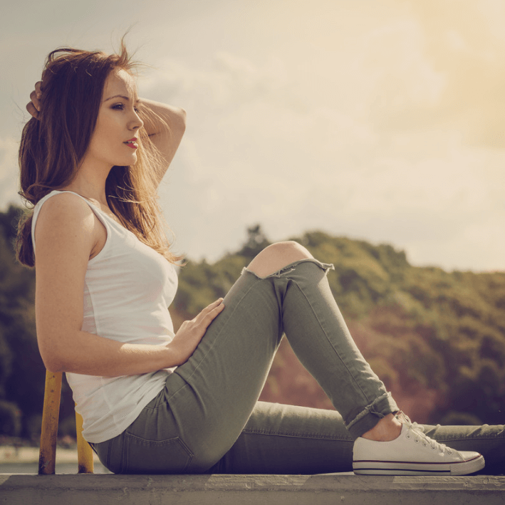 Mulher relaxando ao sol, usando creme reparador fresco para uma pele sedosa e suave.