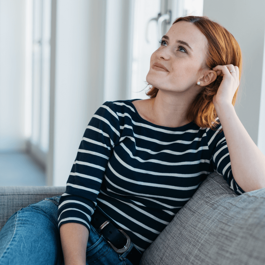Adesivo Pure Harmony woman relaxing on a couch with a thoughtful expression while enjoying her beauty routine.