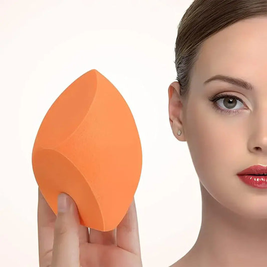 Modelo segurando um esponja de maquiagem laranja em primeiro plano, mostrando o formato e textura do produto.